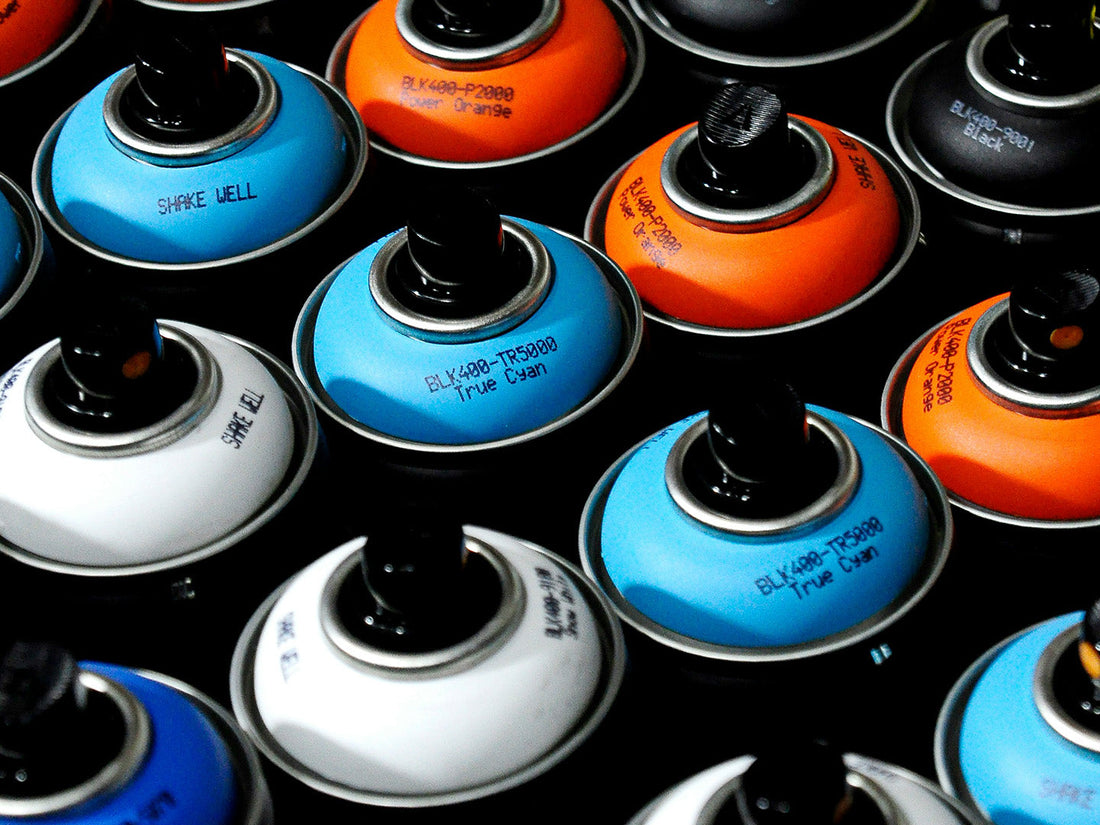Close-up of graffiti spray paint cans showing different colours and nozzle caps