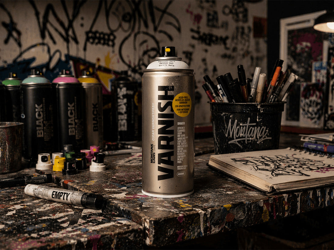 Montana spray varnish can on paint-splattered workbench with graffiti tools and markers in studio setting