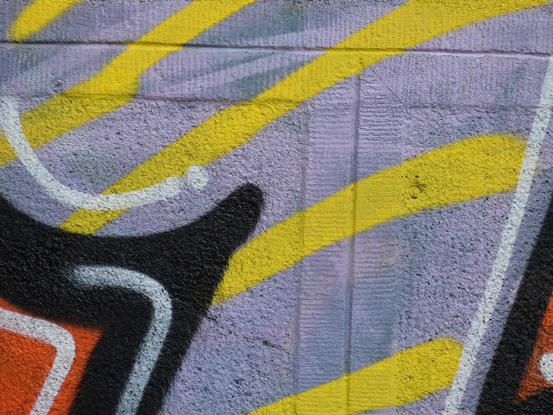 Urban graffiti close-up with sharp black outlines and layered colour on textured surface